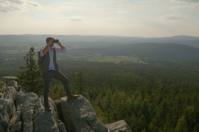 Werner steht auf einem Berg im Fichtelgebirge und hält Ausschau durch ein Fernglas