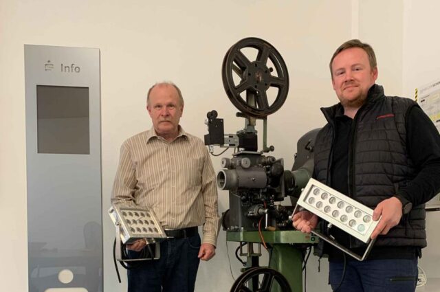 Zwei Männer mit Beleuchtung in der Hand mit einer sehr alten Film Apparatur