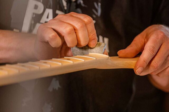 Instrumente Nahaufnahme Gitarre mit Händen und Schleifpapier