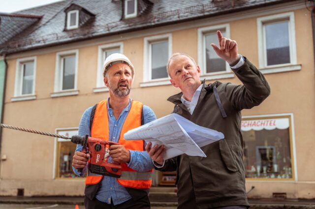 Werner steht vor einem Gebäude mit Leerstandsmanager Markus Bauernfeind